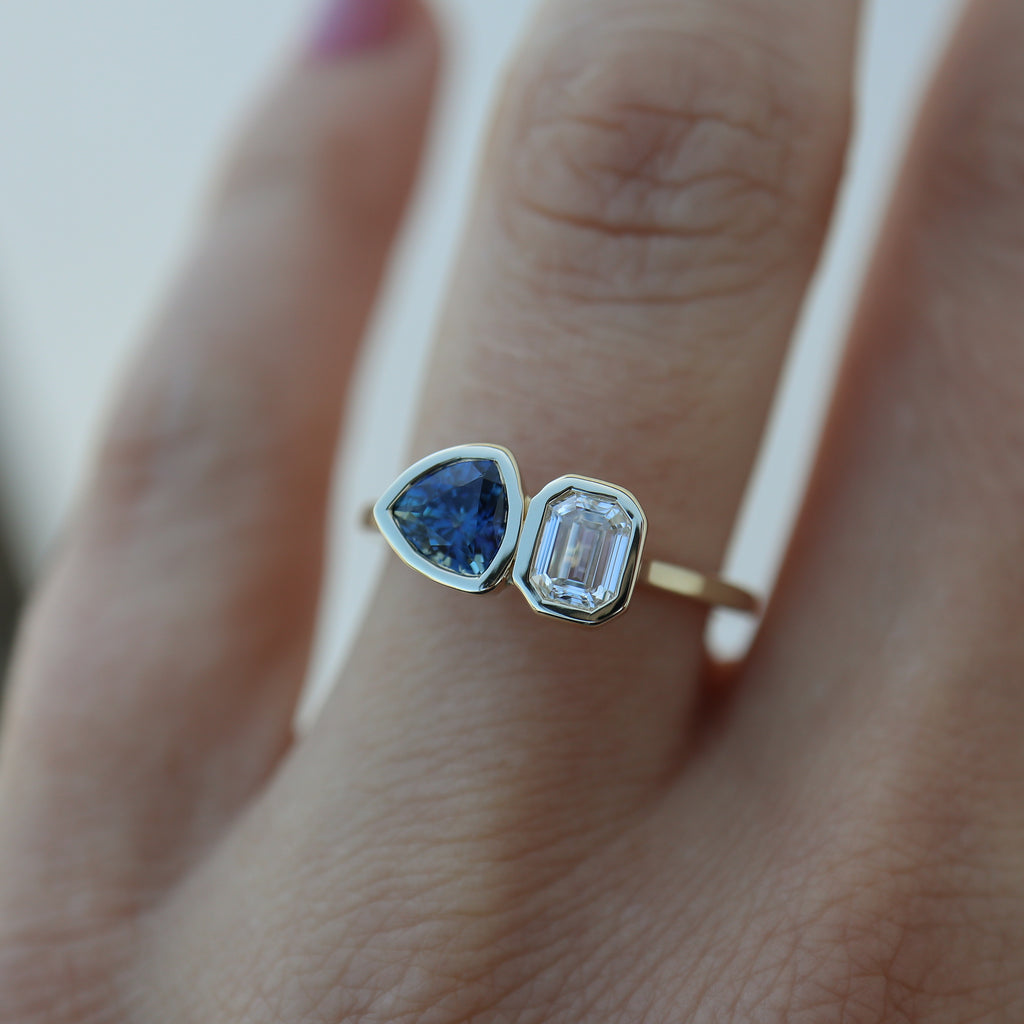 Diamond and sapphire engagement ring on a ring finger.