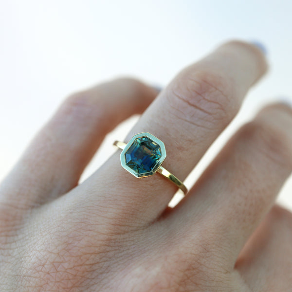 Green sapphire engagement ring on model’s ring finger.